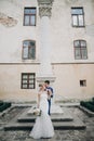 Stylish bride and groom kissing sensually in sunny european city street. Gorgeous wedding couple of newlyweds embracing at old Royalty Free Stock Photo