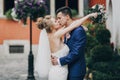 Stylish bride and groom kissing sensually in sunny european city street. Gorgeous wedding couple of newlyweds embracing at old Royalty Free Stock Photo