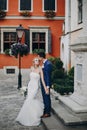 Stylish bride and groom kissing sensually in sunny european city street. Gorgeous wedding couple of newlyweds embracing at old Royalty Free Stock Photo