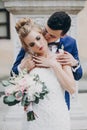 Stylish bride and groom kissing sensually in sunny european city street. Gorgeous wedding couple of newlyweds embracing at old Royalty Free Stock Photo