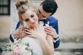 Stylish bride and groom kissing sensually in sunny european city street. Gorgeous wedding couple of newlyweds embracing at old Royalty Free Stock Photo