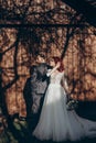 Stylish bride and groom posing in sunlight on background of wooden wall in country. rustic wedding concept in barn, space for text Royalty Free Stock Photo