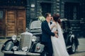 stylish bride and groom sensually posing near retro car with boh Royalty Free Stock Photo