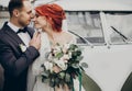 Stylish bride and groom sensually posing near retro car with boho bouquet. luxury wedding couple newlyweds embracing. space for Royalty Free Stock Photo