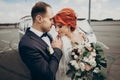 Stylish bride and groom sensually posing near retro car with boho bouquet. luxury wedding couple newlyweds embracing. space for Royalty Free Stock Photo