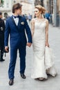 Stylish bride and groom walking in city street. happy luxury wedding couple holding hands in light . romantic sensual moment. Royalty Free Stock Photo