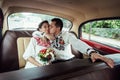 Stylish bride and happy groom inside of retro car having fun and kissing Royalty Free Stock Photo