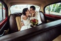 Stylish bride and happy groom inside of retro car having fun and kissing Royalty Free Stock Photo