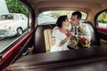 Stylish bride and happy groom inside of retro car having fun and kissing Royalty Free Stock Photo