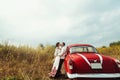 Stylish bride and happy groom near red retro car on the background of nature Royalty Free Stock Photo