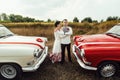Stylish bride and happy groom near  two retro cars on the background of nature Royalty Free Stock Photo