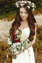 stylish bride posing with bouquet on background of forest, luxury gorgeous boho wedding at mountains