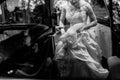 Stylish bride in vintage white wedding dress getting into black limousine with groom, happy couple sitting in car before wedding Royalty Free Stock Photo