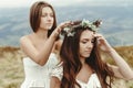 stylish bridesmaid helping gorgeous bride preparing, boho wedding, luxury ceremony at mountains