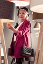 Stylish bright aging madam selecting new floor-lamp in lighting store