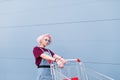 Stylish bright girl with colored hair poses with a shopping cart on a blue background Royalty Free Stock Photo