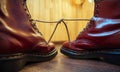 Stylish bright red boots with thick white laces tied together, close-up. April Fools` day, pranks and fun Royalty Free Stock Photo