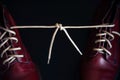 Stylish bright red shoes with thick white laces tied together, close-up, selective focus, space for text. April Fools` day, prank Royalty Free Stock Photo