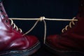 Stylish bright red shoes with thick white laces tied together, close-up, selective focus, space for text. April Fools` day, prank Royalty Free Stock Photo