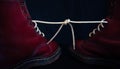 Stylish bright red shoes with thick white laces tied together, close-up, selective focus, space for text. April Fools` day, prank Royalty Free Stock Photo