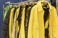 Stylish bright women`s clothing on hangers in the store. Fashionable jackets, trousers, dresses and jumpers