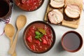 Stylish brown clay bowl with Ukrainian borsch served on white tablecloth, flat lay Royalty Free Stock Photo