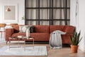 Stylish brown corner sofa with patterned pillows in elegant living room interior with mullions wall Royalty Free Stock Photo