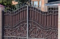 Stylish brown iron gate with a pattern and brick columns Royalty Free Stock Photo