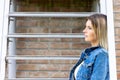 Stylish brunette girl wearing jeans vest, white t-shirt and yellow jeans posing against stairs in the city , urban Royalty Free Stock Photo