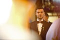 Stylish brunette smiling groom in a suit with a brown bow holds Royalty Free Stock Photo