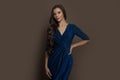Stylish brunette woman wearing blue evening dress on brown background Royalty Free Stock Photo