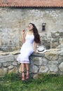 Stylish brunette woman in white dress on background of brick wall Royalty Free Stock Photo