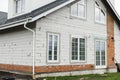 Stylish building with unfinished facade, white windows, modern black roof and dormer. Modern new farmhouse building exterior