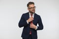 Stylish businessman wearing eyeglasses and looking away while fixing tie Royalty Free Stock Photo