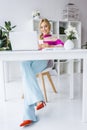 stylish businesswoman in flared jeans sitting at workplace with laptop Royalty Free Stock Photo