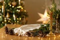 Stylish candle, golden lights, pine cones and ornaments on wooden table against stylish decorated christmas tree with festive