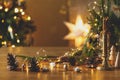 Stylish candle, golden lights, pine cones and ornaments on wooden table against stylish decorated christmas tree with festive