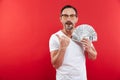 Stylish caucasian man 30s in casual white t-shirt wearing glasses holding lots of money prize dollar currency and pointing finger