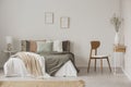 Stylish chair next to warm king size bed in scandinavian bedroom Royalty Free Stock Photo