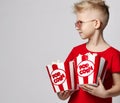 Stylish cheerful boy child in red t-shirt holding pop corn in hands looking away over white background. Trendy casual
