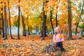 Stylish child girl 5-6 year old wearing trendy pink coat in autumn park. Looking at camera. Autumn season. Childhood.