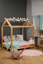 Stylish child room interior with wooden bed in shape of house and toys Royalty Free Stock Photo