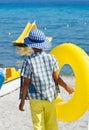 Stylish child wearing colorful clothes and holding yellow float at beach Royalty Free Stock Photo