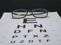 Stylish children glasses on a visual testing chart isolated on black Royalty Free Stock Photo