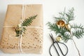 Stylish christmas gift. Modern christmas gift box with fir branch, golden bell, festive paper and ornaments composition on white