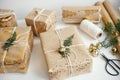 Stylish christmas gifts. Modern christmas gift boxes with fir branch, golden bell, festive paper and ornaments composition on