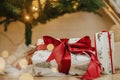 Stylish christmas gifts under christmas tree with golden lights bokeh. Wrapped christmas presents with red ribbon under decorated Royalty Free Stock Photo