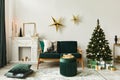 Stylish christmas living room interior with green sofa, white chimney, christmas tree and wreath, stars, gifts and decoration. Royalty Free Stock Photo