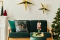 Stylish christmas living room interior with green sofa, white chimney, christmas tree and wreath, stars, gifts and decoration. Royalty Free Stock Photo