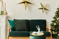 Stylish christmas living room interior with green sofa, white chimney, christmas tree and wreath, stars, gifts and decoration. Royalty Free Stock Photo